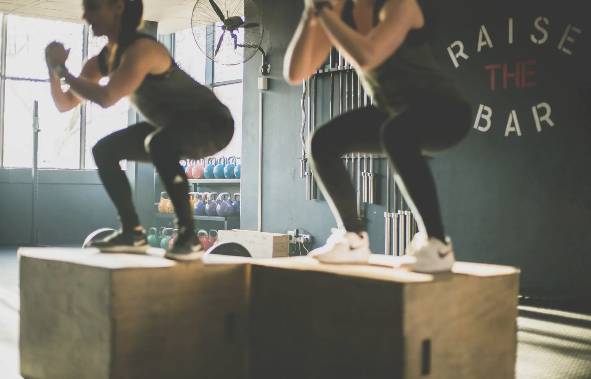 Two people training on plyometric boxes in a gym