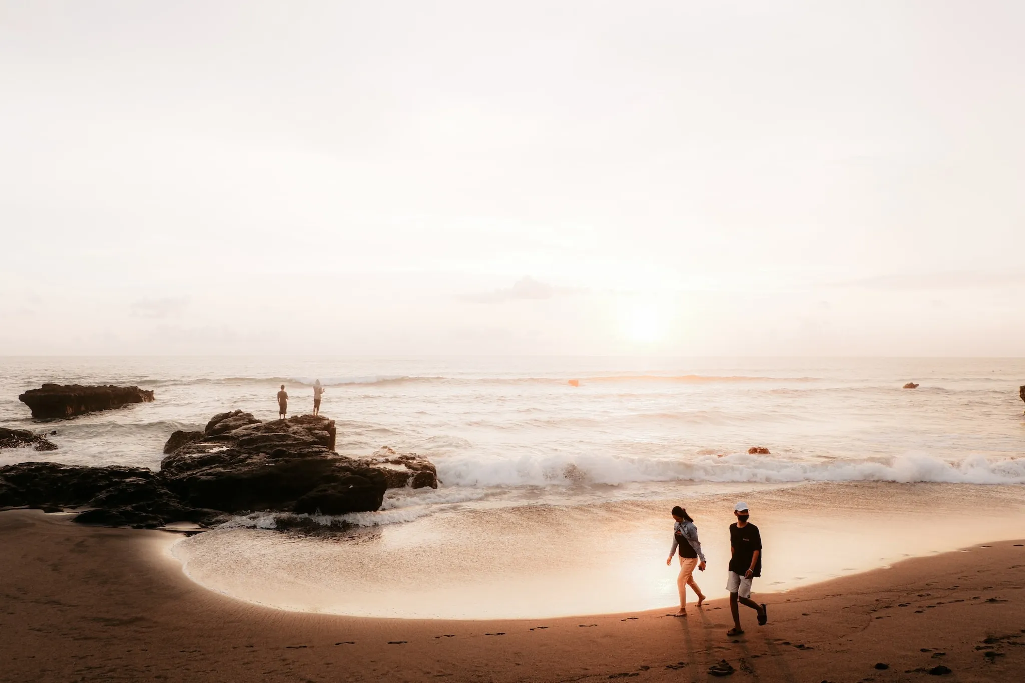 Two people walking along the beach at sunset
