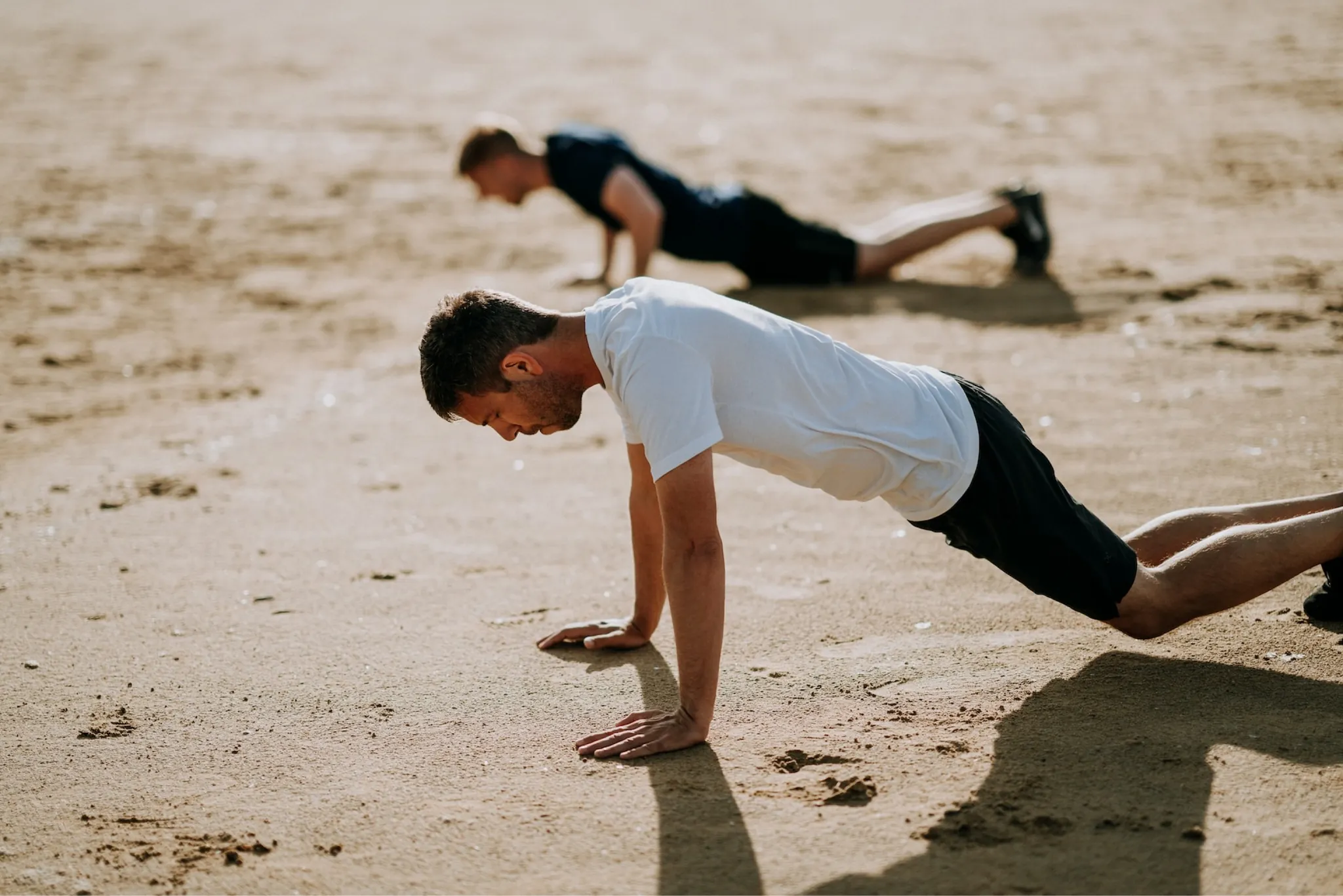 Two men holding plank positions on the sand
