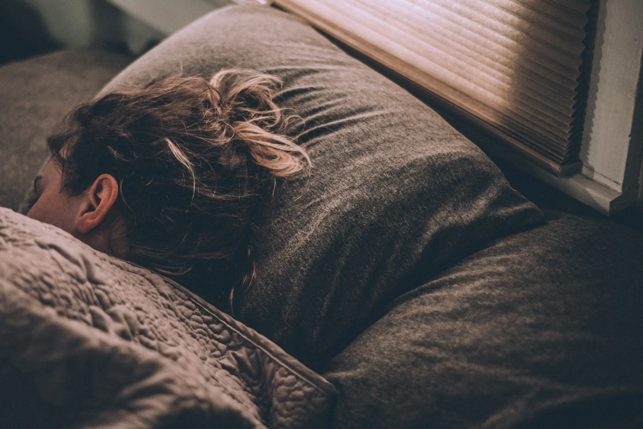 A person asleep under a grey blanket
